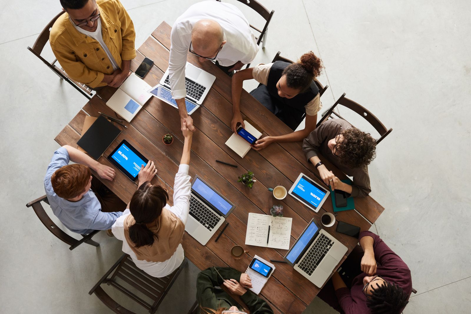 Equipe reunida em torno de uma mesa, trabalhando em conjunto com notebooks e tablets